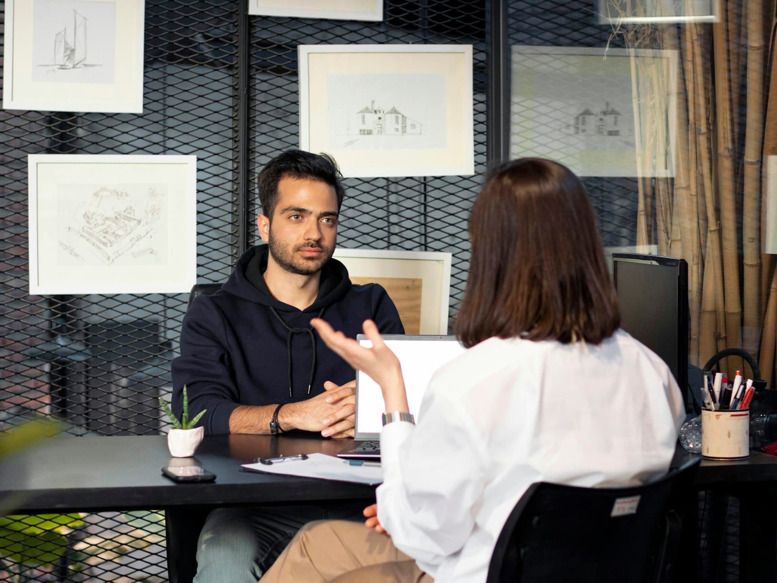 Opdrachtgever en IT-professional in gesprek aan een bureau