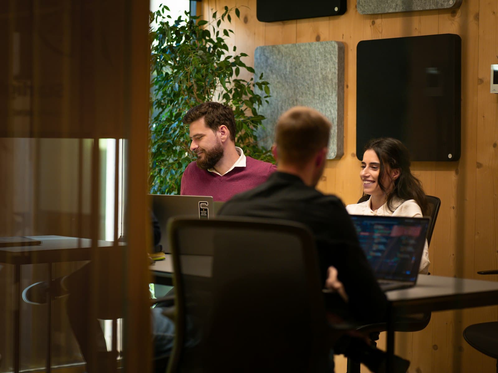 Drie professionals in overleg aan tafel met laptops op kantoor